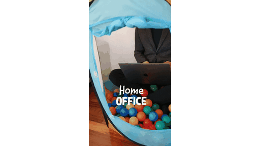 Thuiswerker met laptop in een speeltent vol ballen